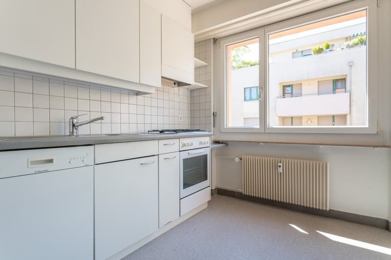 modern kitchen with white cabinets, tiled walls, stainless steel sink, gas stove, dishwasher, washing machine, window