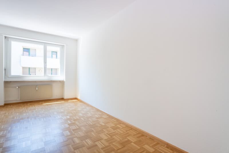empty room, wooden parquet floor, white walls, large window, radiator