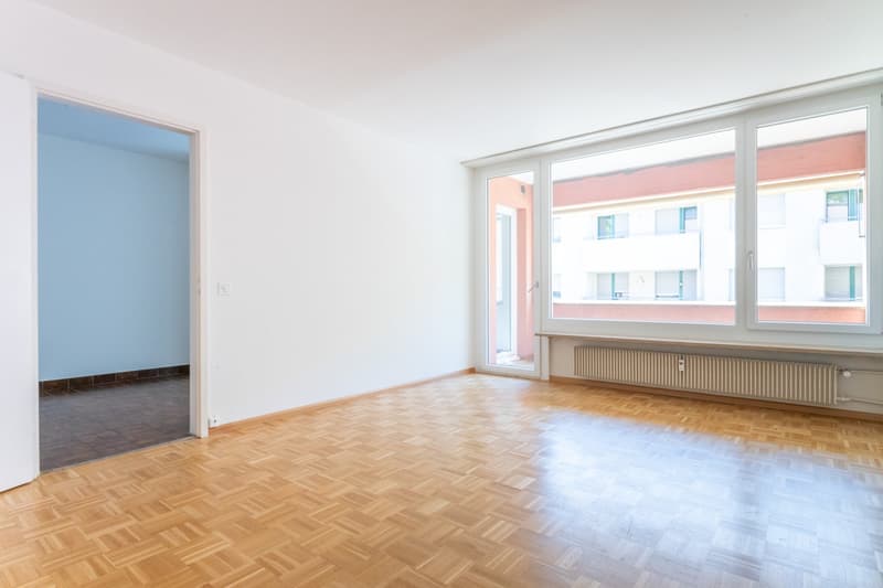 empty room, wooden parquet floor, large windows, white walls, sliding glass door