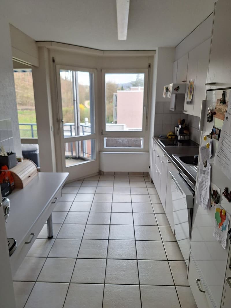 modern kitchen with white tiles, white cabinets, large windows, balcony, refrigerator, sink, gas stove