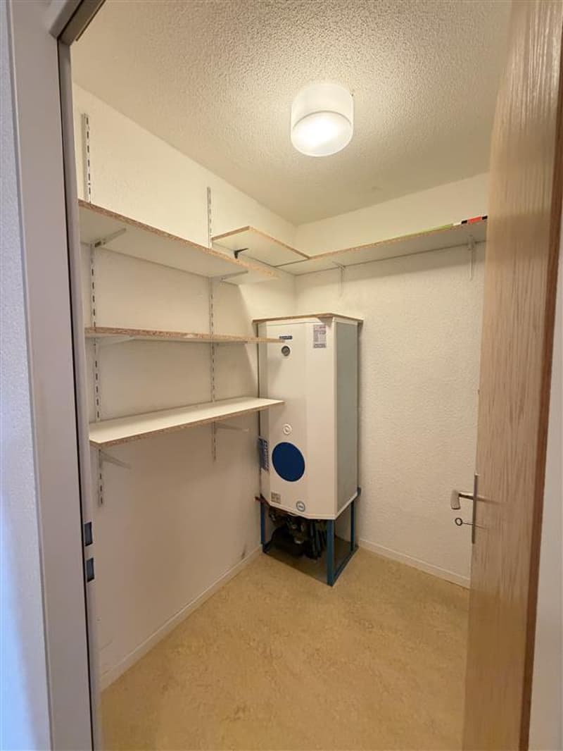 empty room with shelves, water heater, light on the ceiling