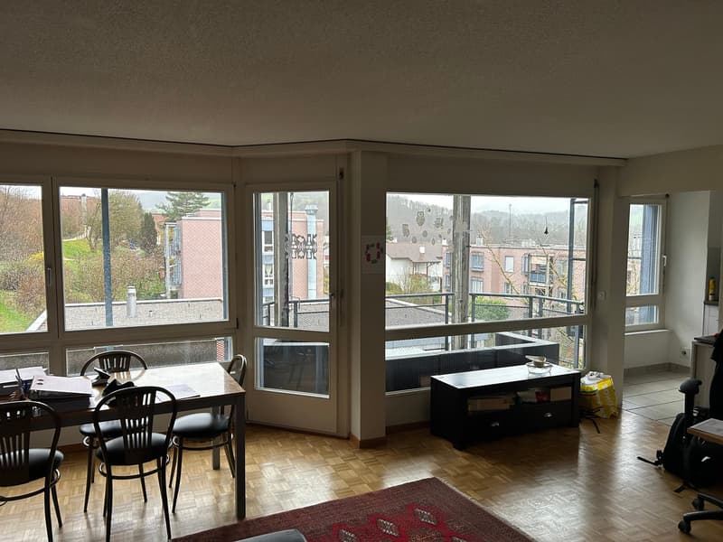 large windows, wooden floor, dining table, chairs, rug, black cabinet, view of the outside