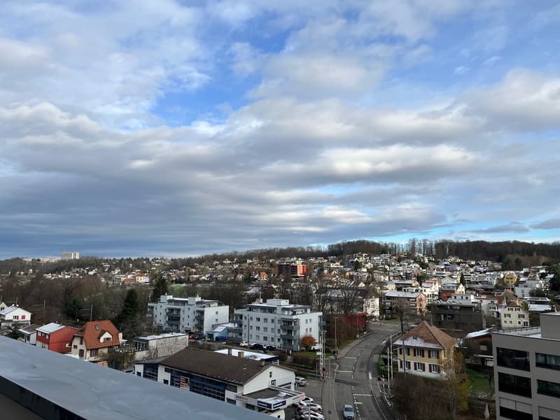 Aerial view of a town with many buildings, a road, and a cloudy sky