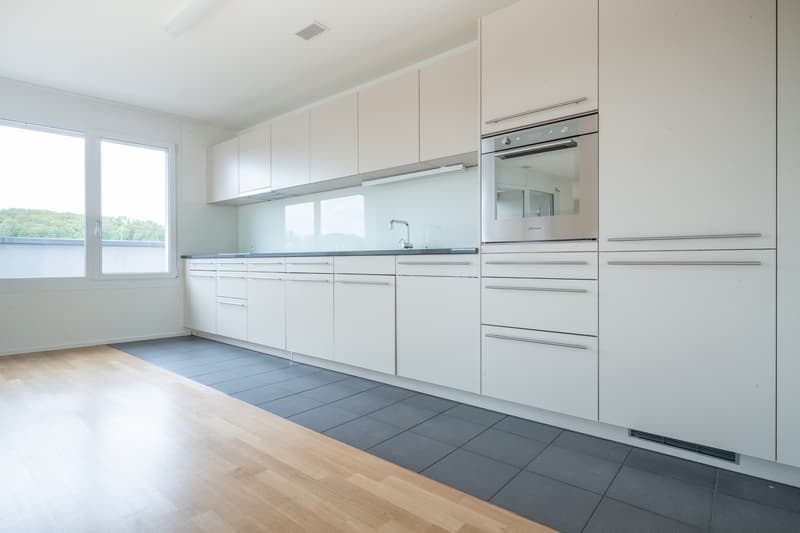 modern kitchen with white cabinets, wooden floor, stainless steel oven, sink, and faucet