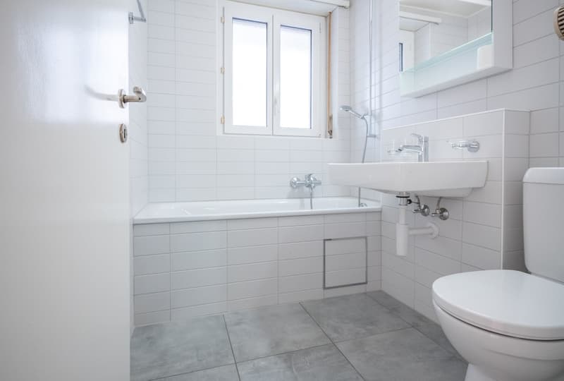 Bathroom with white tiles, bathtub, sink, toilet, and shower