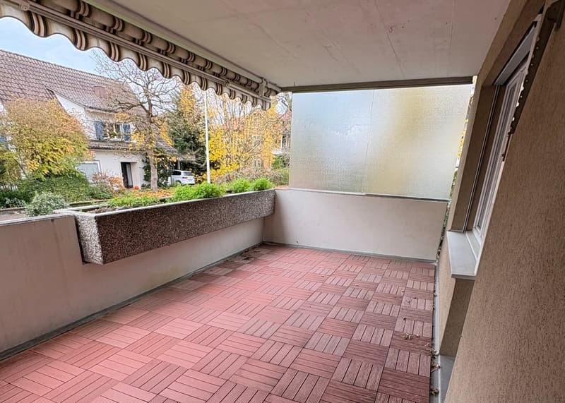 Balcony with wooden floor, wall-mounted planter, glass wall, and awning