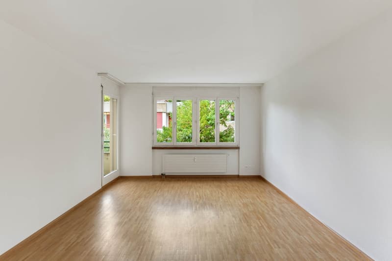 empty room with wooden floor, large windows, white walls, heating unit