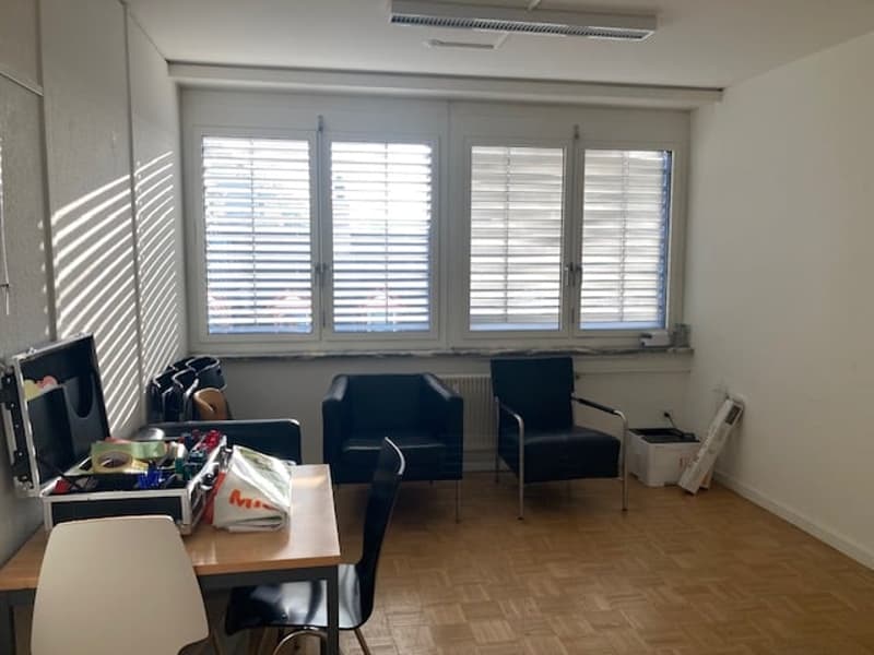 empty room with table, chairs, suitcase, bags, and windows with shutters