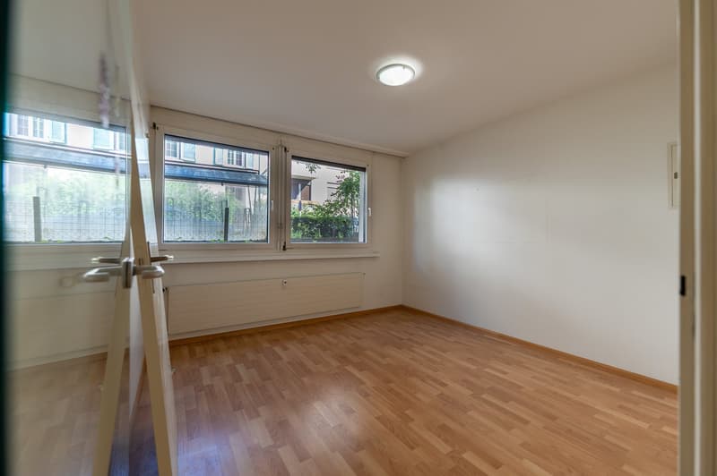 empty room, wooden floor, white walls, two large windows, ceiling light, radiator