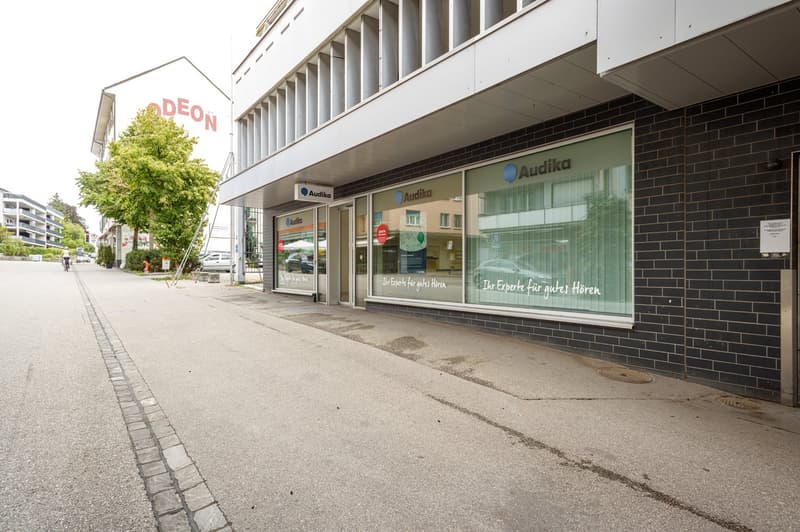 front of building, glass windows, logo, entrance doors, brick wall, street, traffic sign, trees, sidewalk