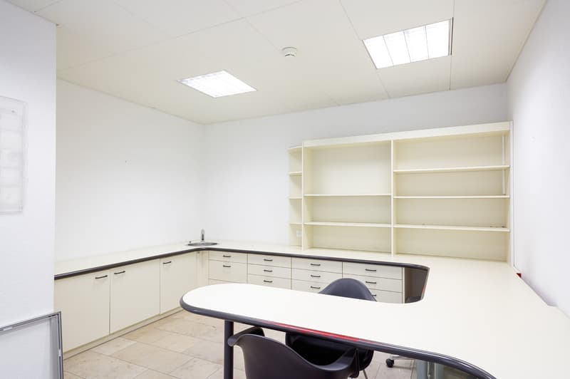 white shelves, desk, sink, two chairs, white tiles, bright lighting