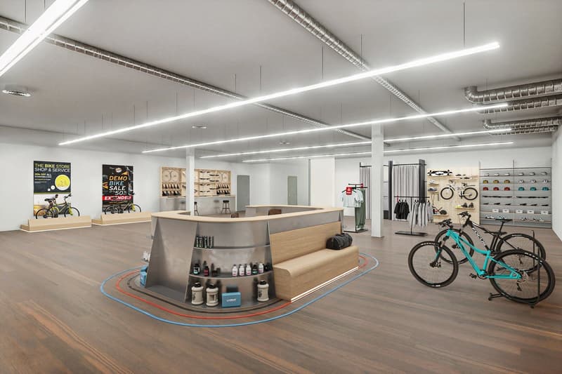 An open space shop with wooden floor, multiple shelves, counter, clothes rack, bicycles, banners, lamps