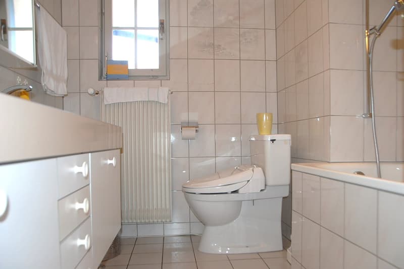Bathroom with white tiles, sink, white toilet, bathtub, radiator, showerhead