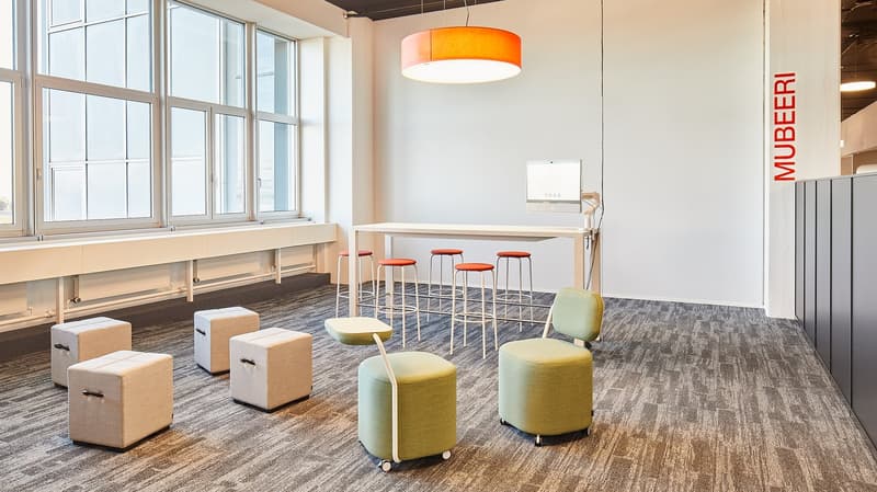 modern office room with large windows, white desk, stools, round chairs, carpeted floor, pendant light