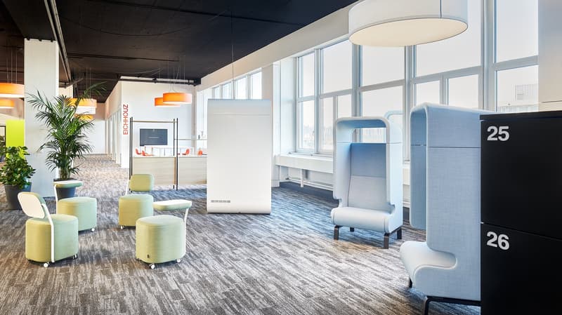 modern office space with carpeted floor, large windows, modern furniture, plants, and pendant lights