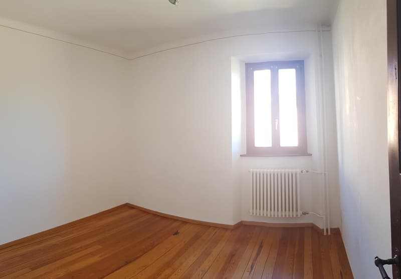 Empty room with white walls, hardwood floor, and a window with double-paned glass.