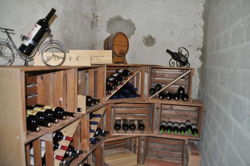 Wooden wine cellar with bottles, wine racks, wooden box, barrel, and bicycle