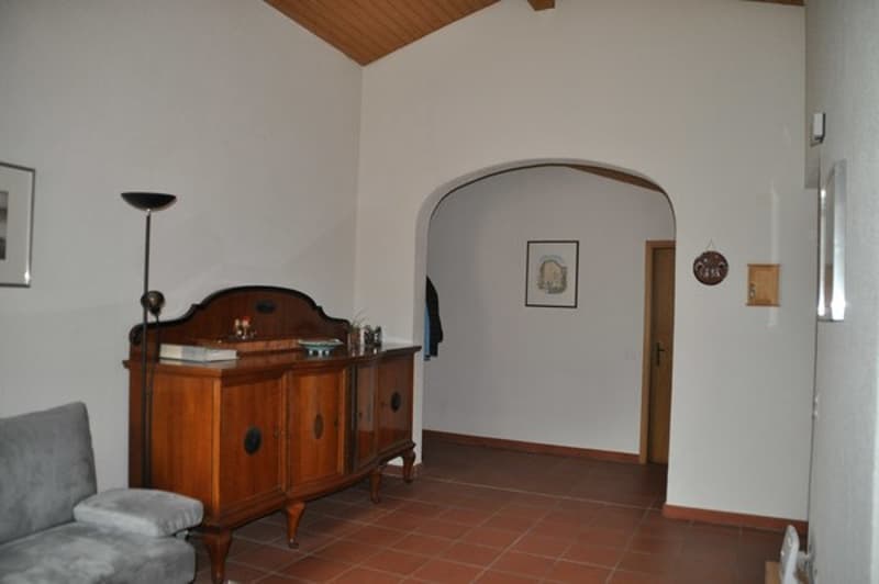 empty room with couch, wood floor, cabinet, picture frame, and lamp