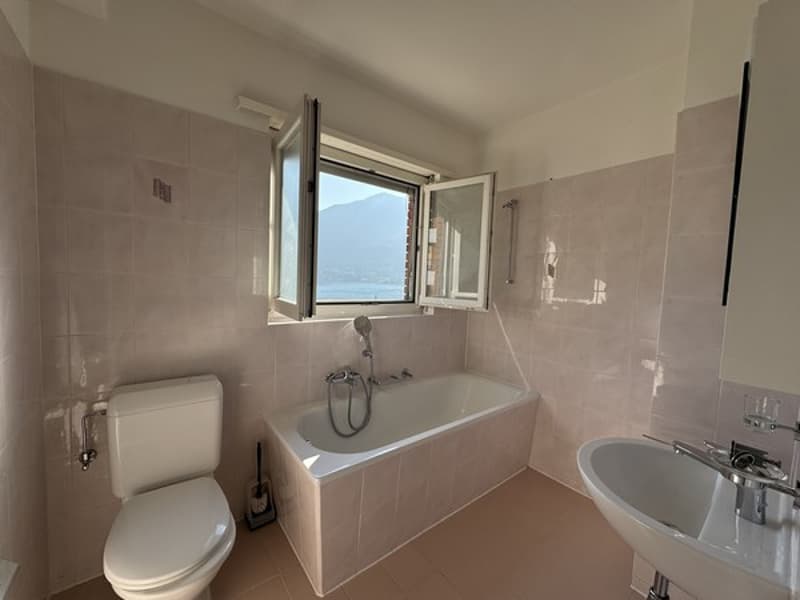 white tiles, bathtub, toilet, sink, shower head, window with mountain view