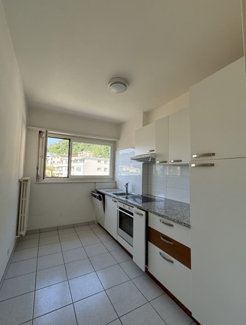 modern kitchen with white cabinetry, tile flooring, granite countertops, integrated appliances, including dishwasher and oven, ample natural light from window