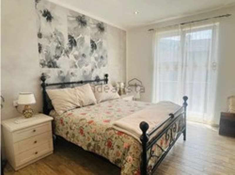 bedroom with a bed, lamp, nightstand, and white curtains