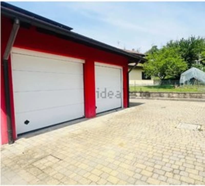 Red building with 2 garages and parking lot in front