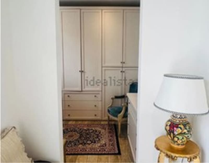 White closets, a blue chair, a rug, a table with a lamp
