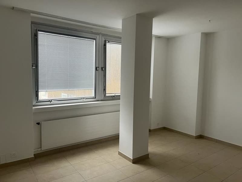 Empty room with white walls, tiled floor, white radiator and windows with blinds