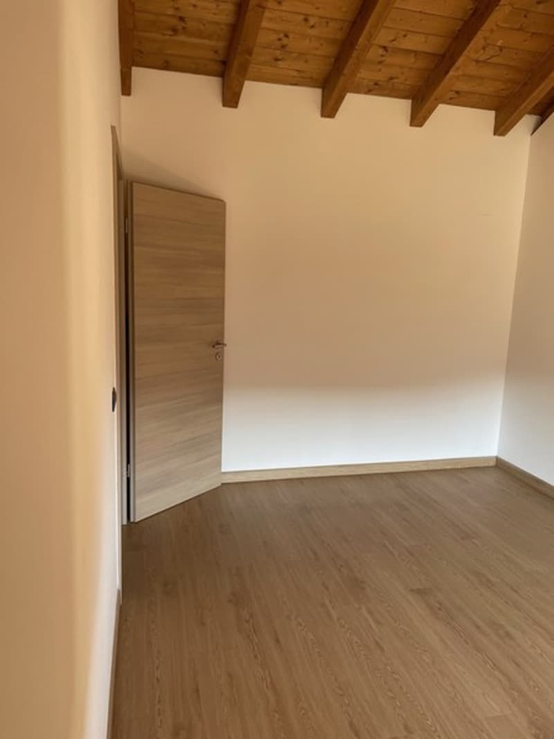 Empty room with wooden door, wooden ceiling, wooden flooring, and white walls