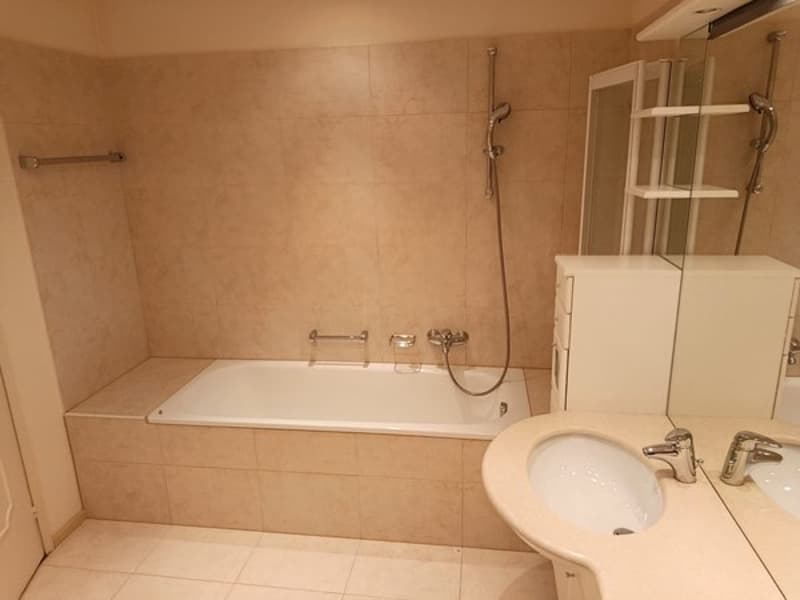 Bathroom with bathtub, double sink, mirror, showerhead, and shower rod.