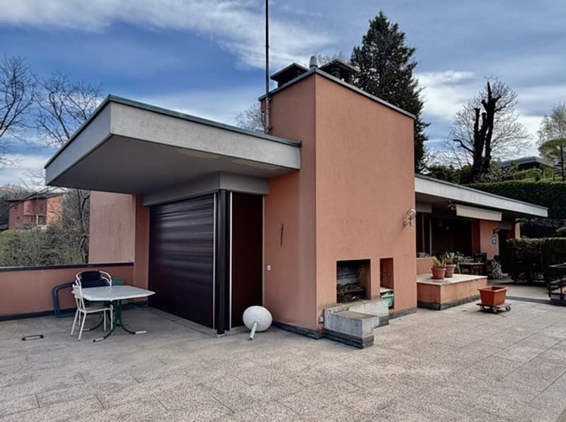 modern house, pink exterior, black garage door, outdoor fireplace, balcony, table and chairs