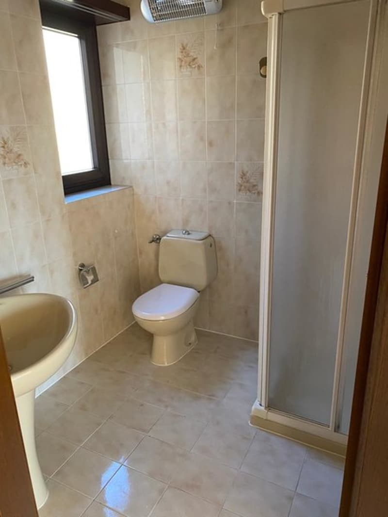 Tiled bathroom with toilet, shower, and washing machine