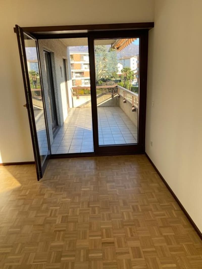 Spacious room with hardwood flooring, large sliding glass doors leading to a balcony or terrace, and a view of the outdoor area.