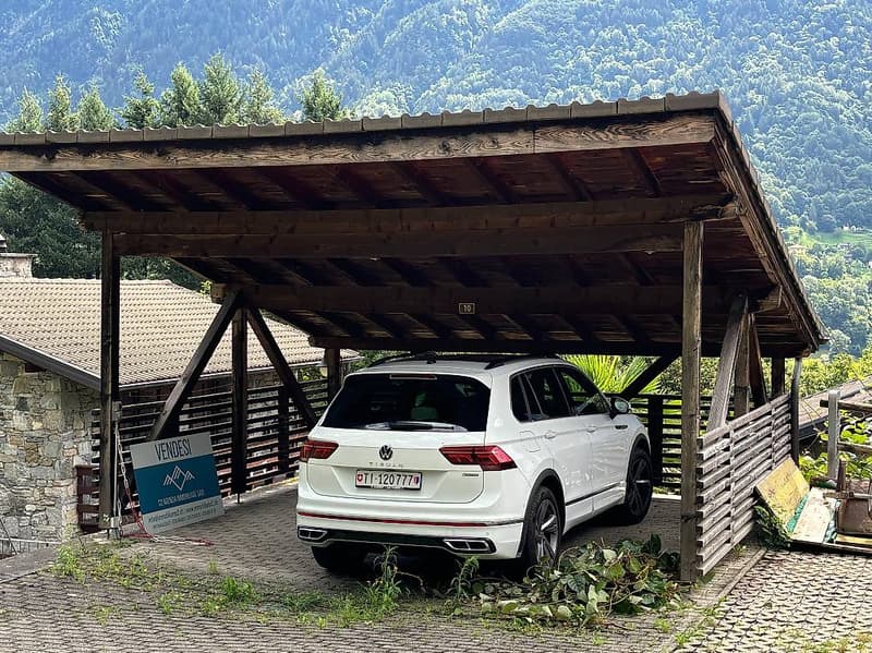 Car parked under a wooden carport with a view of a valley in the background