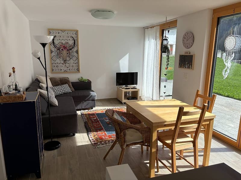 open floor plan, wooden desk, wicker chairs, couch, carpet, rug, framed wall art, lamps, clock, television, cabinet, balcony, window