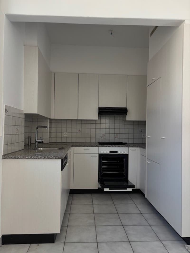 modern kitchen with white cabinets, granite countertop, stainless steel sink, oven, dishwasher, and washing machine