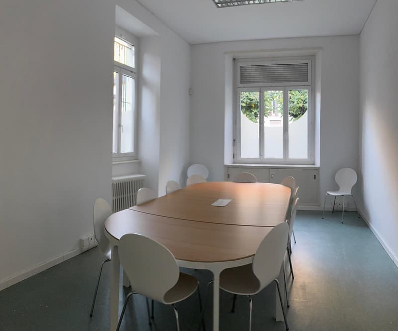 empty room, long table, white chairs, white walls, windows, radiator