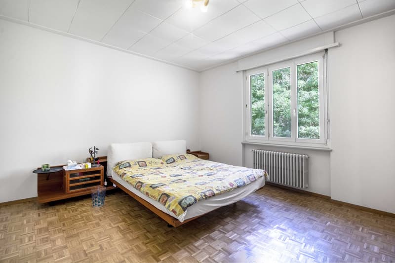 Bedroom with bed, nightstand, and window with view of trees