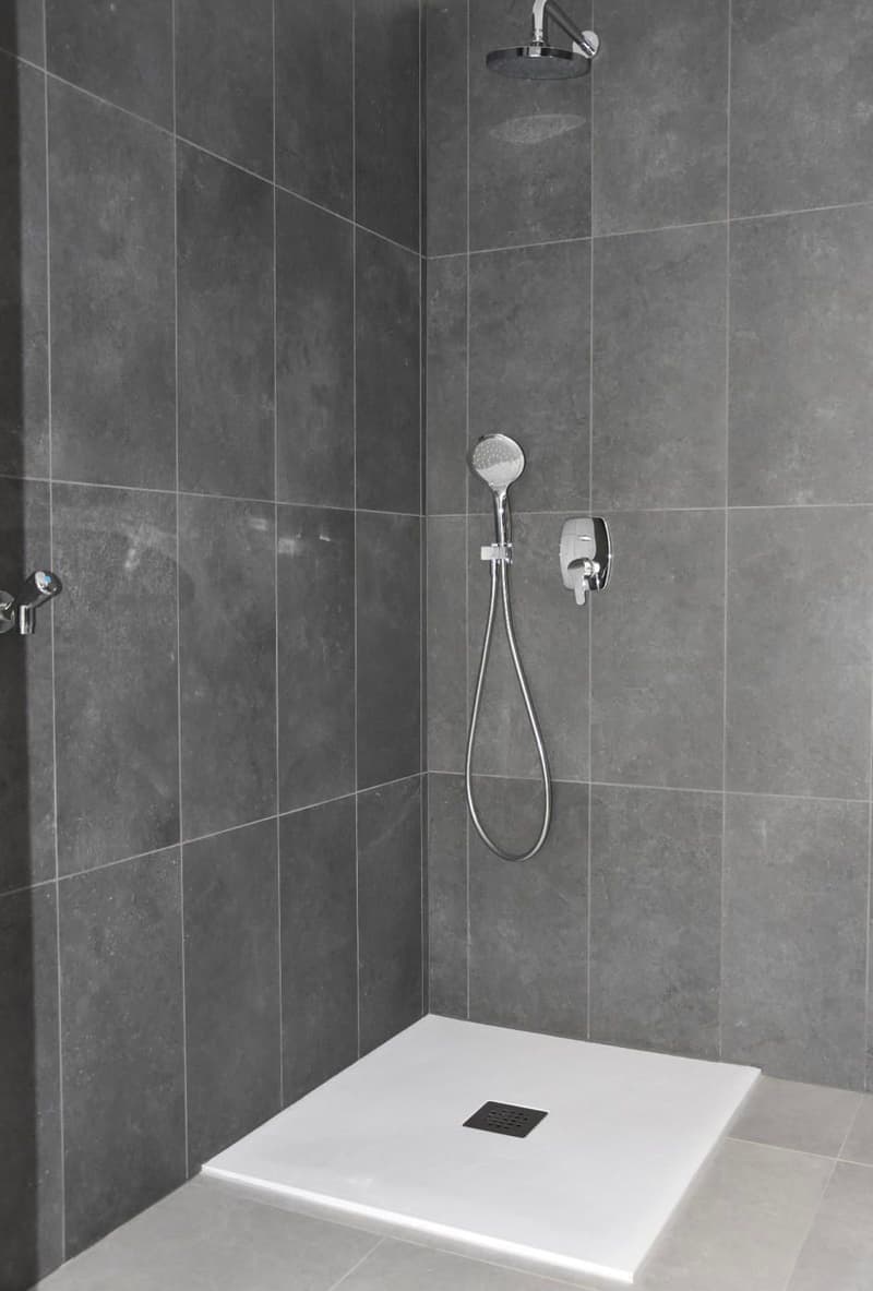 Shower area with gray tile walls, white shower tray, and a shower head and faucet fixture.
