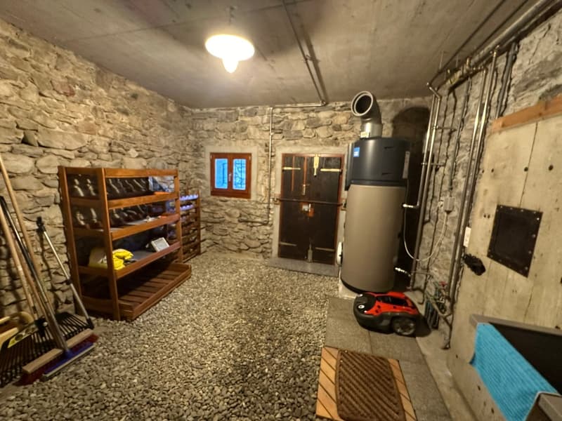 Stone wall, wooden shelf, heating unit, window, gravel floor, door
