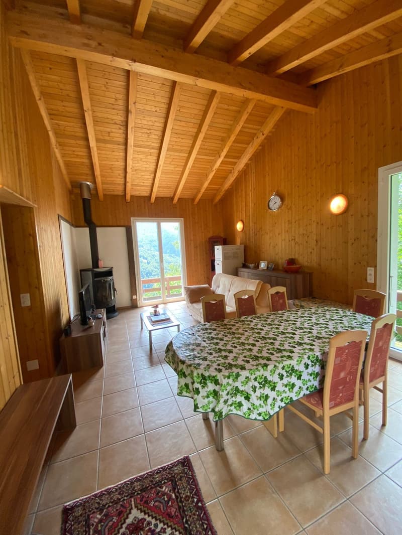 wood paneled walls, wooden ceiling beams, fireplace, dining table with chairs, couch, glass doors