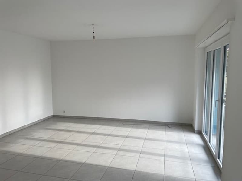 Large open space with white walls, tile flooring, and a sliding glass door leading to an exterior area.
