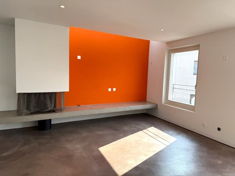 room with orange accent wall, concrete bench, white walls, grey floor, built-in fireplace