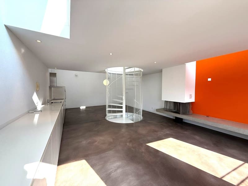 Spacious room with white walls, floor and ceiling, orange accent wall, white spiral staircase, white countertop, modern kitchen with faucet, fireplace
