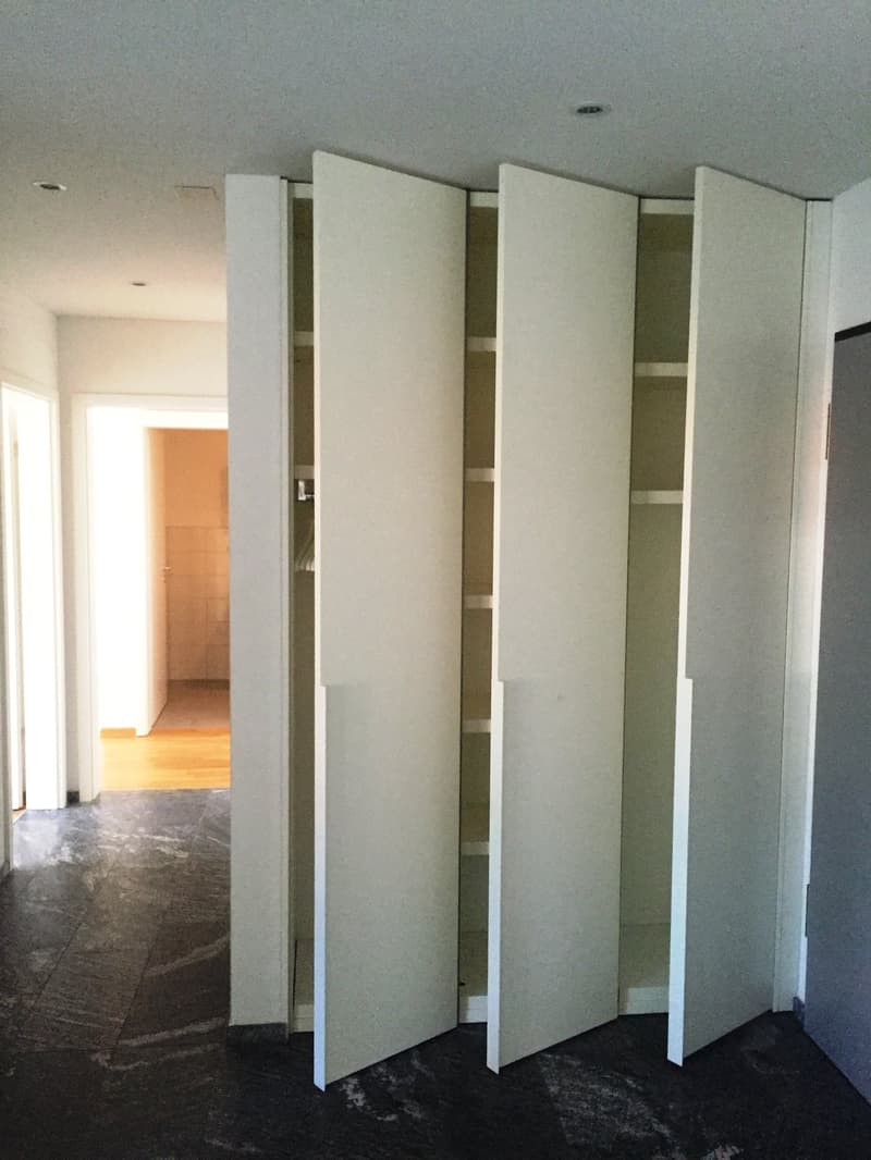 Four open white wardrobes with sliding doors in an empty room