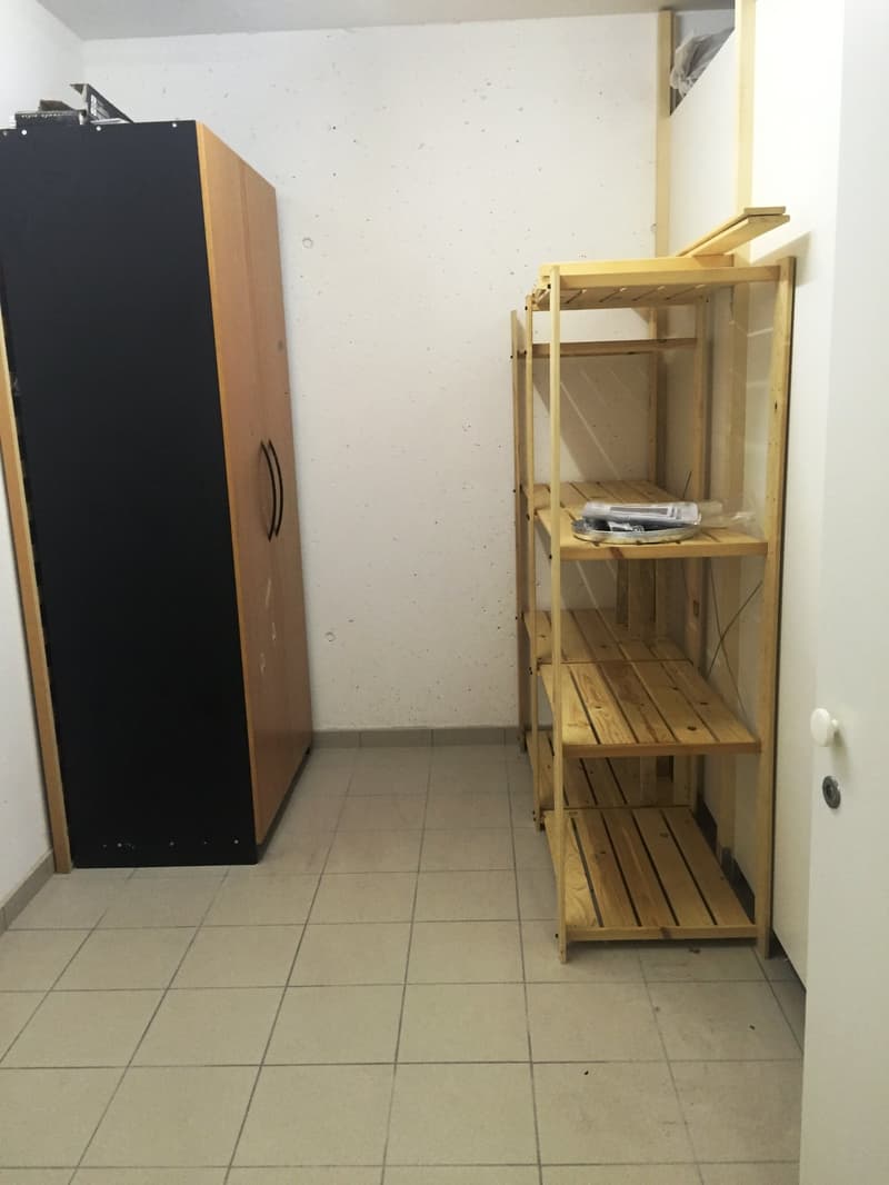 Storage room, wooden shelves, large wardrobe, tiled floor, white walls.