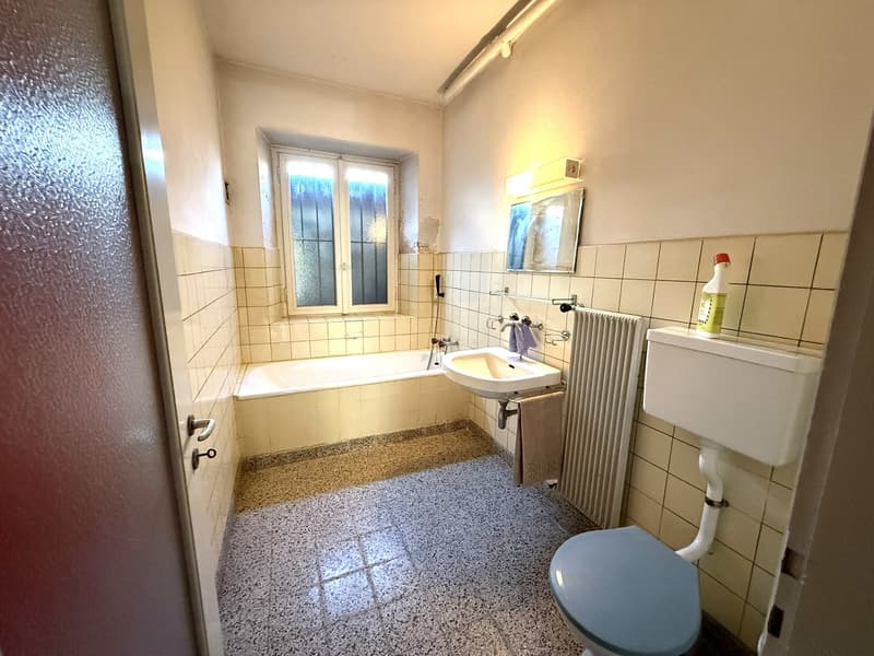 Bathroom with bathtub, sink, toilet, radiator, window, tile flooring, white walls