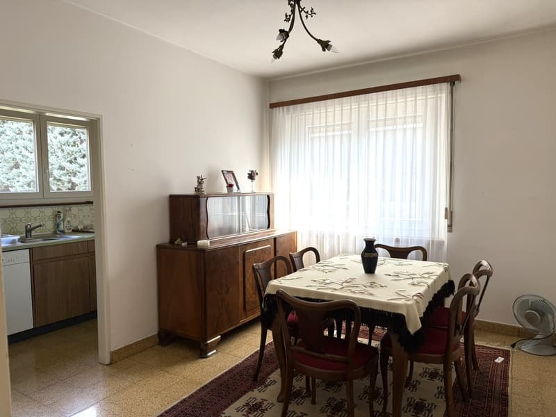 A dining room with a wooden table, chairs, a wooden cabinet, and a sink