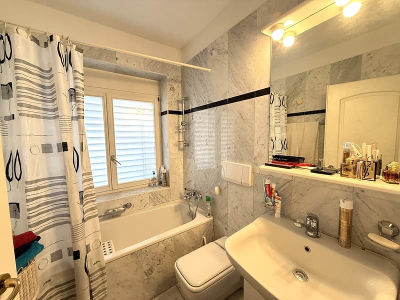Bathroom with bathtub, toilet, sink, mirror, and shower curtain