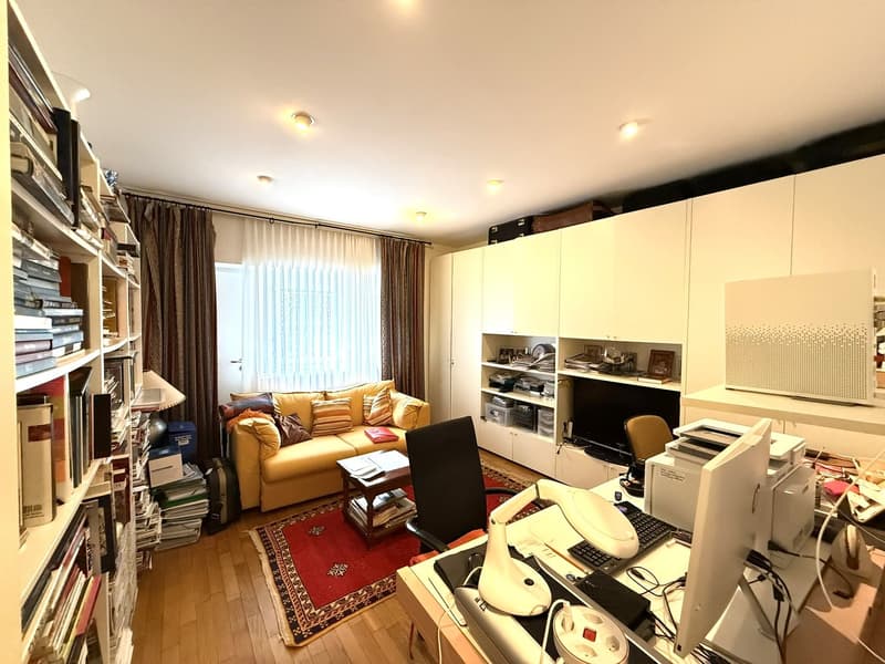 yellow couch, wooden table, computer desk, office chair, bookshelves, white cabinets, shelves, oriental rug, overhead lights, white curtains, monitor, printer, lamp